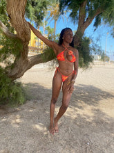Load image into Gallery viewer, Person in an mix of colours orange, yellow and pink bikini posing outdoors on a tree-lined street.