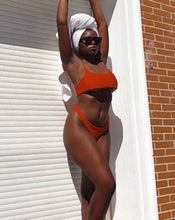 Load image into Gallery viewer, A female Model wearing the Red Ruffle bikini standing against a white wall with a brick background
