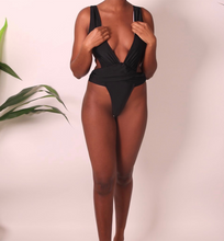 Load image into Gallery viewer, A female model wearing a black one-piece swimsuit with a deep V-neck cutout and high-thigh design.
